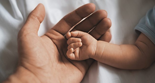 Close-up small hands of baby is lying in men of his father hands, concept of caring, fatherhood Close-up small hands of baby is lying in men of his father hands, concept of caring, fatherhood, family